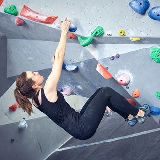 Woman on rock climbing wall at The Climbing Hangar